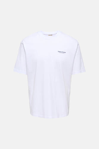 T-shirt blanc à manches courtes ONLY & SONS®, avec un imprimé coloré de fleurs et de têtes au dos, porté avec un jean foncé et des baskets blanches.