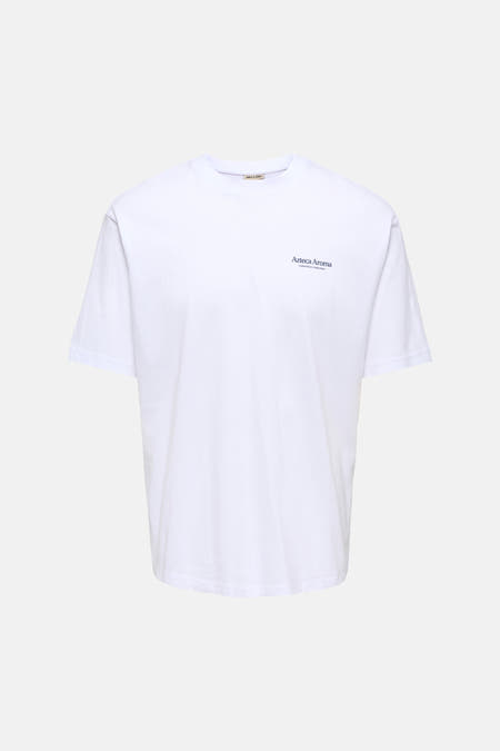 T-shirt blanc à manches courtes ONLY & SONS®, avec un imprimé coloré de fleurs et de têtes au dos, porté avec un jean foncé et des baskets blanches.
