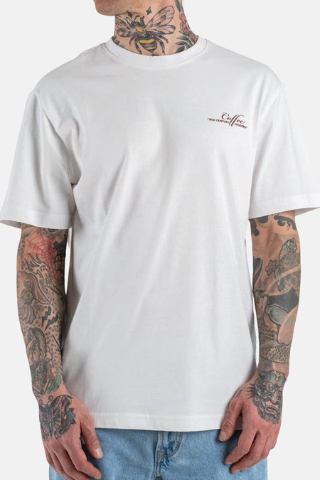 T-shirt blanc à manches courtes ONLY & SONS®, avec petit imprimé texte marron et tatouages sur les bras et le cou.