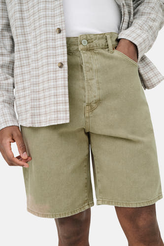 Short en jean de couleur beige de ONLY & SONS avec bouton métallique et texture légère, porté avec une chemise à carreaux et un t-shirt blanc.