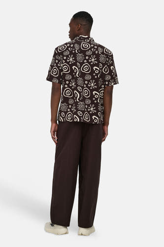 Chemise marron à manches courtes ONLY & SONS avec motifs blancs abstraits, portée par une personne qui détourne le regard.