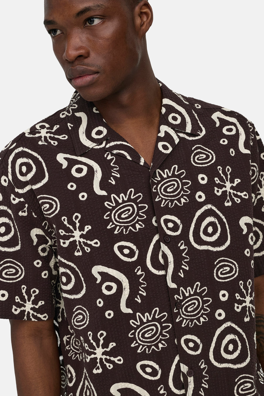 Chemise marron à manches courtes ONLY & SONS® avec texture gaufrée et imprimé abstrait blanc, portée par un homme.