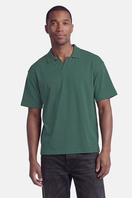 Polo verte de ONLY & SONS avec col en V ouvert, manches courtes, portée par un homme avec un jean noir.