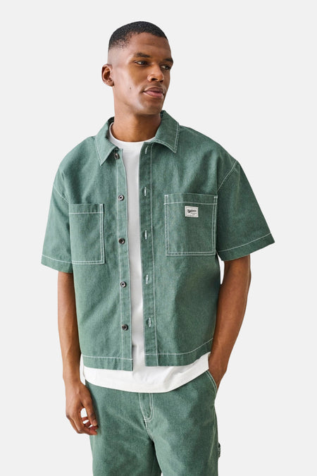 Chemise verte à manches courtes ONLY & SONS® avec surpiqûres contrastées blanches, deux poches poitrine et short assorti.