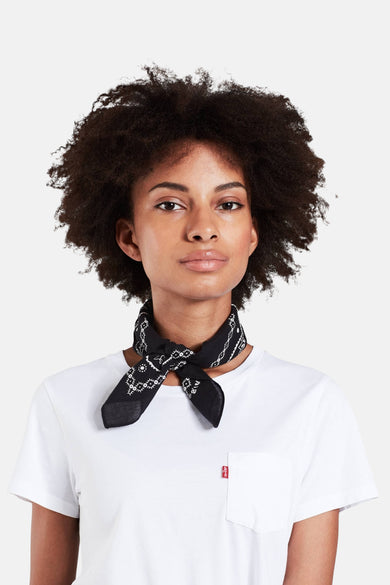 Een vrouw met een afro draagt een zwarte bandana en een wit t-shirt.
