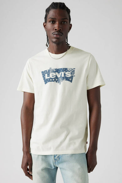 T-shirt beige à manches courtes de Levi's® avec logo bleu sur la poitrine et porté avec une chaîne d'argent.