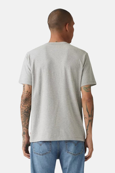 Achterkant van een man in een grijs T-shirt en blauwe jeans.