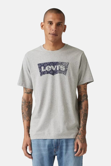 Een man met een grijs Levi's T-shirt met blauwe logo en lichte jeans.