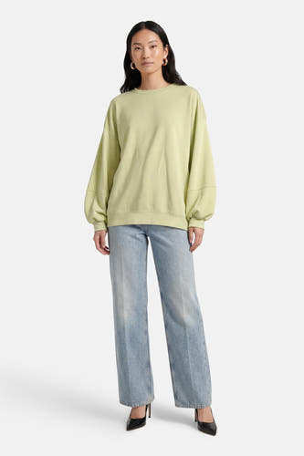 Groene sweater van Terra di Siena, met lange mouwen en gecombineerd met wijde jeans en zwarte pumps.
