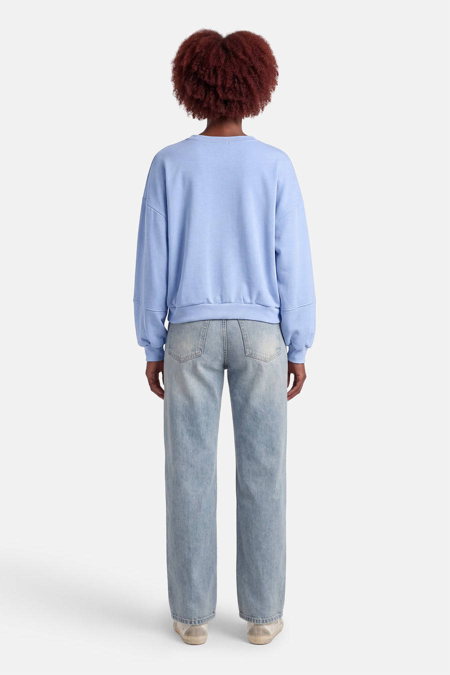 Pull bleu à col rond de Terra di Siena, vu de dos, combiné avec un jean bleu clair et des baskets basses.