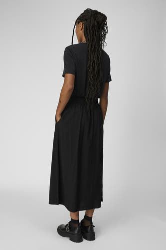 T-shirt noir d'OBJECT, vu de dos, avec une longue jupe et des chaussures noires.
