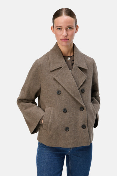 Manteau court brun d'OBJECT, avec une fermeture à double bouton et des poches, associé à un jean foncé.