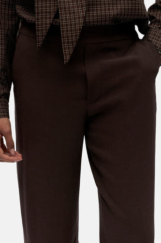 Pantalon marron d'OBJECT, avec un tissu lisse et une ceinture discrète, combiné avec une chemise à carreaux.