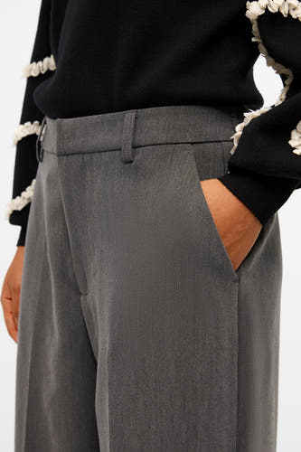 Pantalon de costume gris d'OBJECT, avec poche et passants, porté avec une chemise noire.