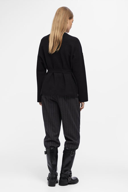 Zwart gilet van OBJECT, met ceintuur in de taille, gedragen over een gestreepte broek en zwarte laarzen.
