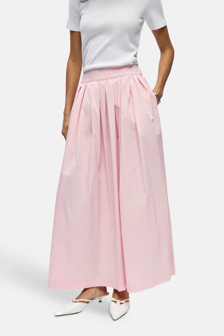 Jupe longue plissée rose d'OBJECT avec poches, portée avec un t-shirt blanc et des chaussures blanches.
