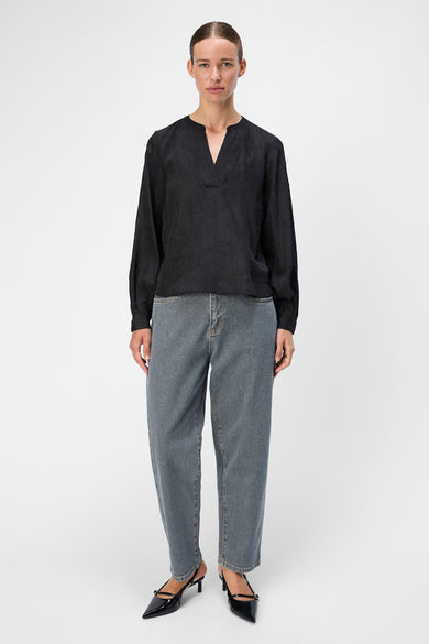 Blouse noire à manches longues d'OBJECT, avec un col V et portée avec des jeans bleus et des bottes noires.