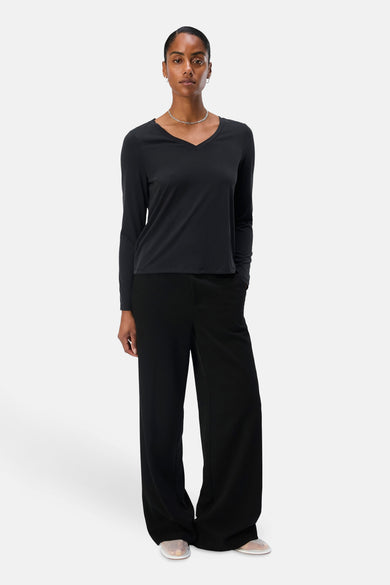 T-shirt noir à manches longues d'OBJECT, avec un col V et porté avec des pantalons noirs larges et des chaussures ouvertes.
