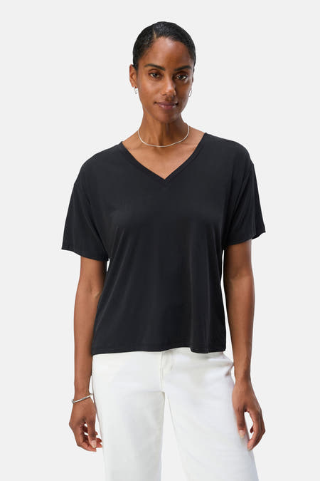 T-shirt noir à manches courtes d'OBJECT, avec un col V, associé à une chaîne argentée et à un pantalon blanc.