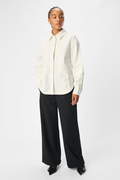 Chemise écru à longues manches d'OBJECT, avec des détails floraux brodés et portée avec un pantalon noir.