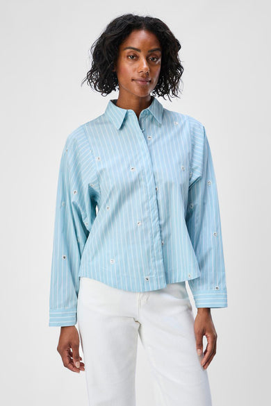 Chemise bleue rayée à manches longues d'OBJECT, terminée avec des éléments décoratifs, portée avec un pantalon blanc.