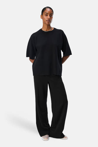 Zwarte trui van OBJECT, met korte mouwen en gedragen met een zilveren ketting en zwarte broek.