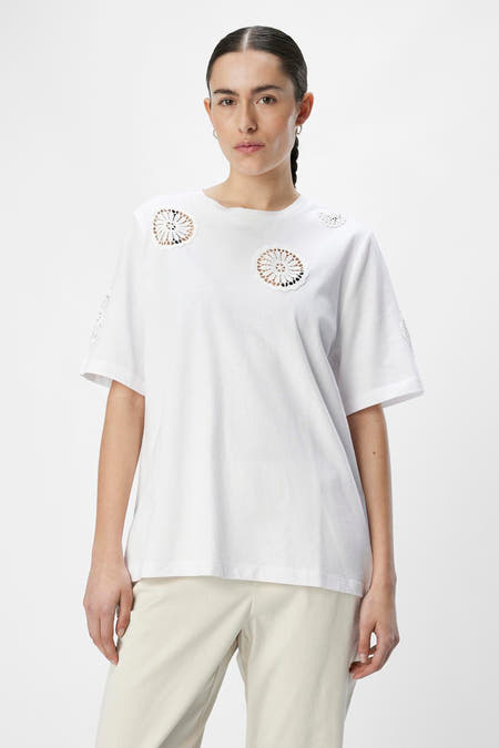 T-shirt blanc à manches courtes d'OBJECT, avec un col rond et des détails décoratifs sur les manches, associé à des pantalons crème et des chaussures noires.