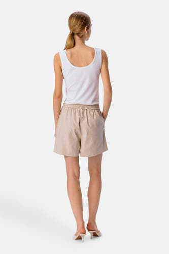 Crème court de OBJECT, avec une ceinture élastique, porté avec un chemisier blanc et des talons.