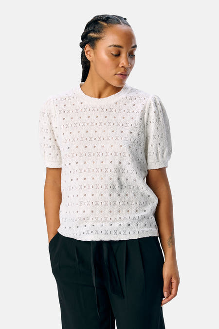 T-shirt blanc à manches courtes d'OBJECT, avec un motif fleuri et porté avec un pantalon noir.