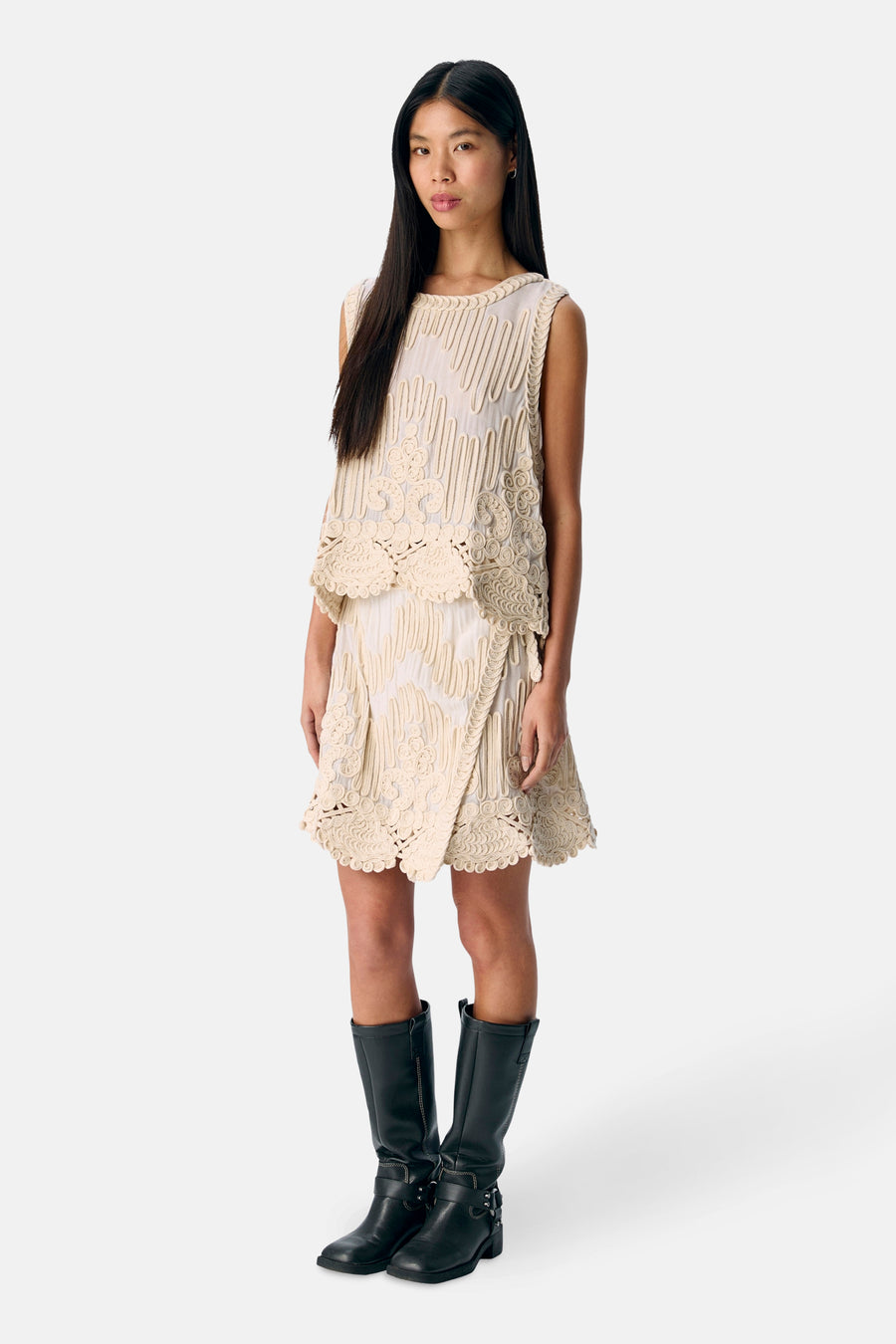 Vrouw in gebroken witte kleding, zwarte laarzen, volle lengte.