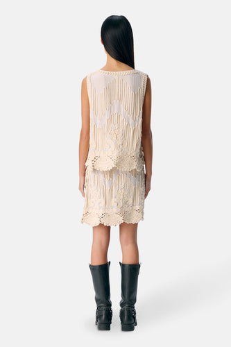 Vrouw van achteren in ecru kleurige jurk met zwarte laarzen.