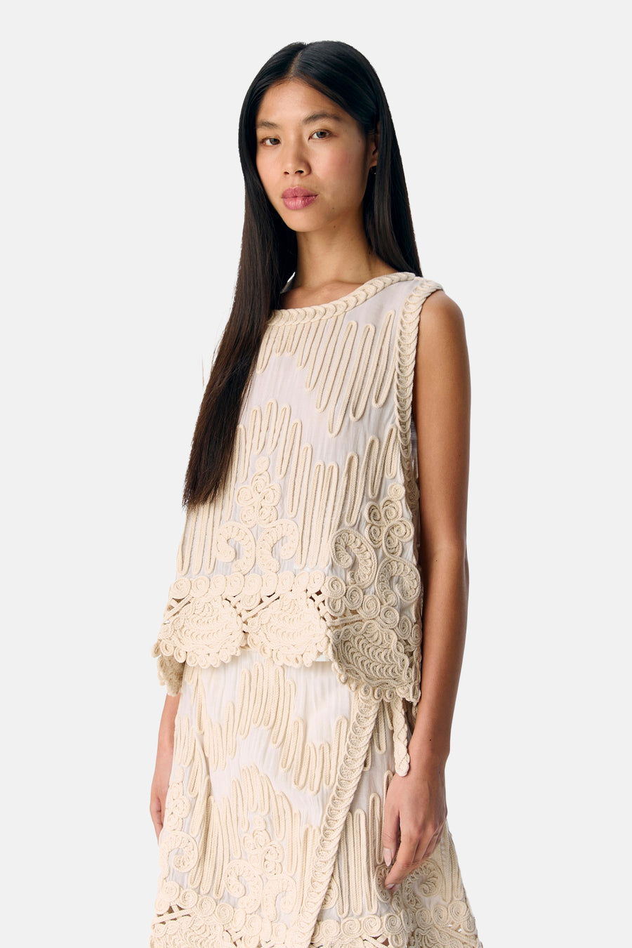 Vrouw in crèmekleurige top en rok met decoratief stiksel.