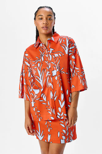 Chemise orange à manches courtes d'OBJECT, avec un motif bleu et blanc frappant et portée avec des bottes noires jusqu'aux genoux.
