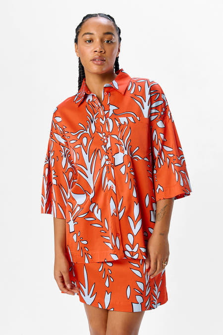 Chemise orange à manches courtes d'OBJECT, avec un motif bleu et blanc frappant et portée avec des bottes noires jusqu'aux genoux.