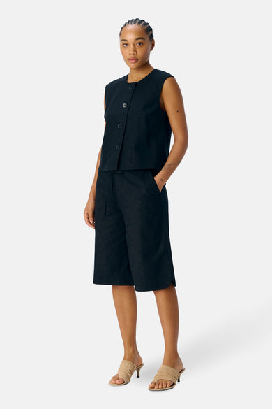 Blazer noir d'OBJECT, porté avec un short coordonné à cordon et des mocassins beige.