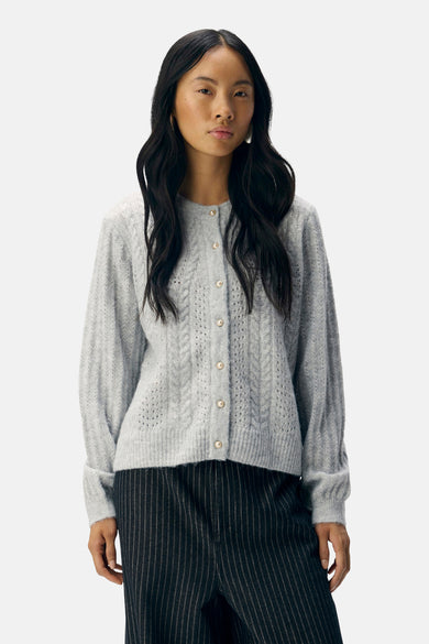 Gilet gris d'OBJECT, avec un motif côtelé et des boutons en perles, associé à un pantalon rayé.