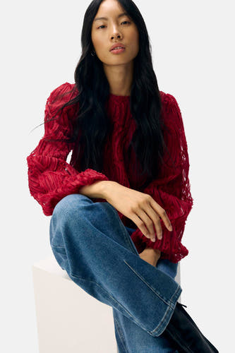 Blouse rouge à longues manches d'OBJECT, avec une texture remarquable, associée à des jeans bleus et des bottes noires.