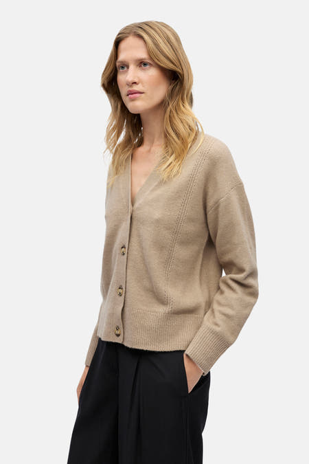 Gilet beige de OBJECT, avec fermeture à boutons, porté sur un pantalon noir à larges jambes.