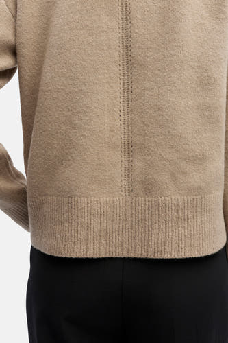 Gilet beige d'OBJECT, avec des broderies décoratives sur le dos et un bord côtelé, porté sur une jupe noire.