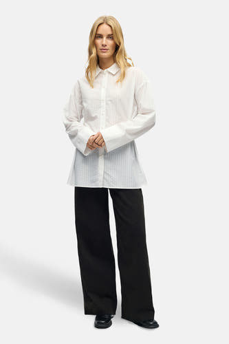Chemise blanche à manches longues d'OBJECT, portée avec des pantalons noirs larges et des chaussures noires.