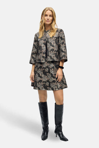 Manteau court brun d'OBJECT, avec un imprimé floral, porté avec une jupe noire et des bottes en cuir noires.