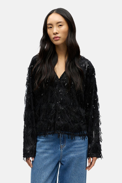 Blouse noire à longues manches d'OBJECT, détaillée avec des paillettes et associée à un jean bleu.