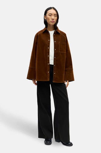 Chemise brune à longues manches d'OBJECT, avec des coutures blanches et portée sur un chemisier blanc avec un pantalon noir.