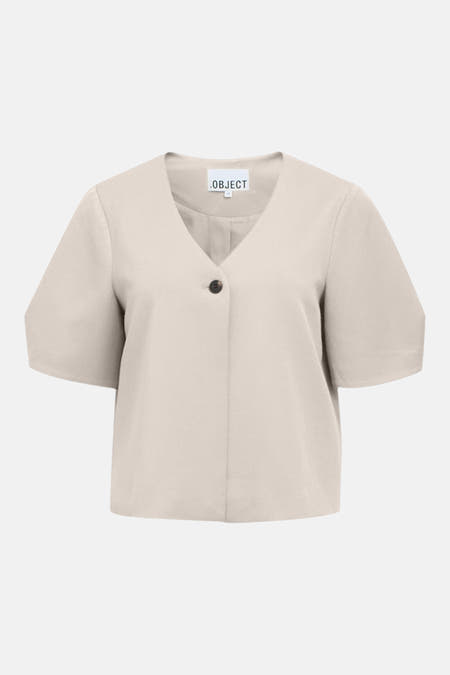 Gilet écru de OBJECT, avec col en V et fermeture à un bouton, porté avec un jean bleu.