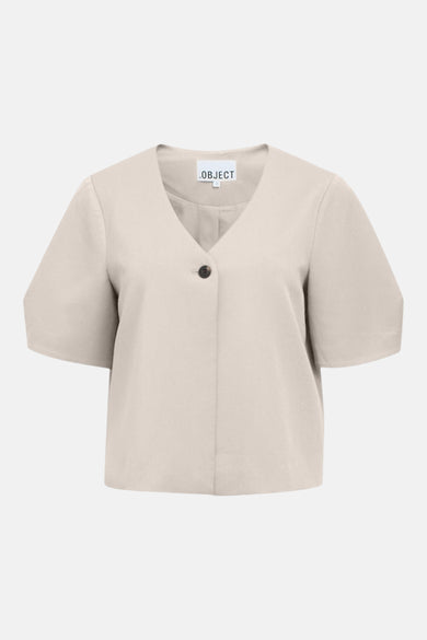 Gilet écru de OBJECT, avec col en V et fermeture à un bouton, porté avec un jean bleu.
