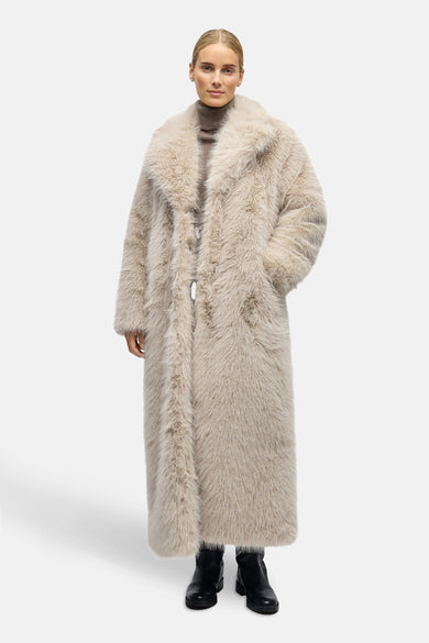 Ecru long manteau d'OBJECT, avec une texture de fourrure douce, col et poches po po porté sur un gilet et des bottes.