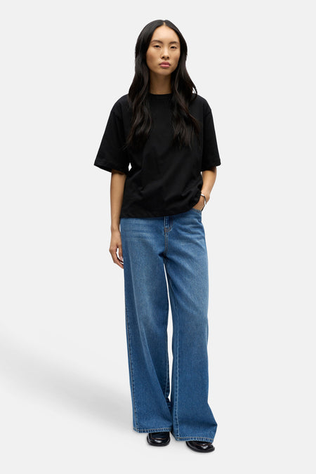 Zwart korte mouwen T-shirt van OBJECT, oversized fit, gedragen met blauwe wijde jeans en zwarte schoenen, front view.