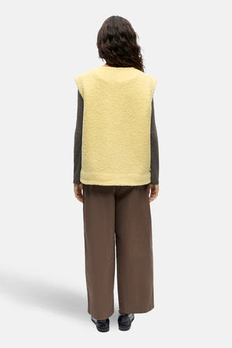 Gele gilet van OBJECT, met een zachte textuur, gedragen over een grijze top en bruine broek, achteraanzicht.
