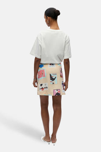 Jupe courte multicolore de OBJECT, avec un motif saisissant et associée à un t-shirt blanc et des mules blanches.