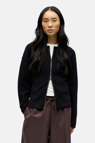Gilet noir d'OBJECT, avec une fermeture éclair argentée et un pantalon marron à cordon.